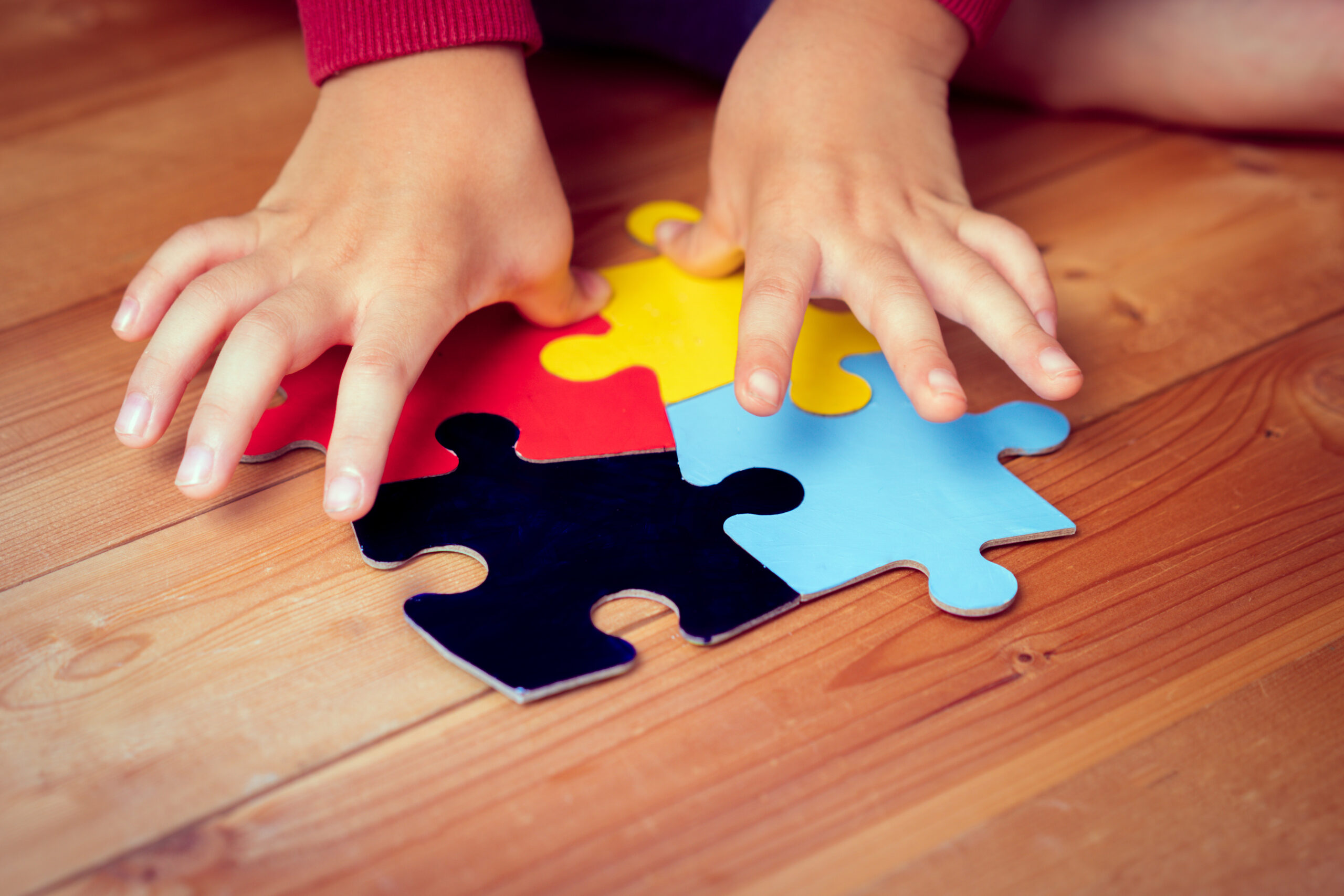 Dziecko z autyzmem ukłąda puzle na podłodze